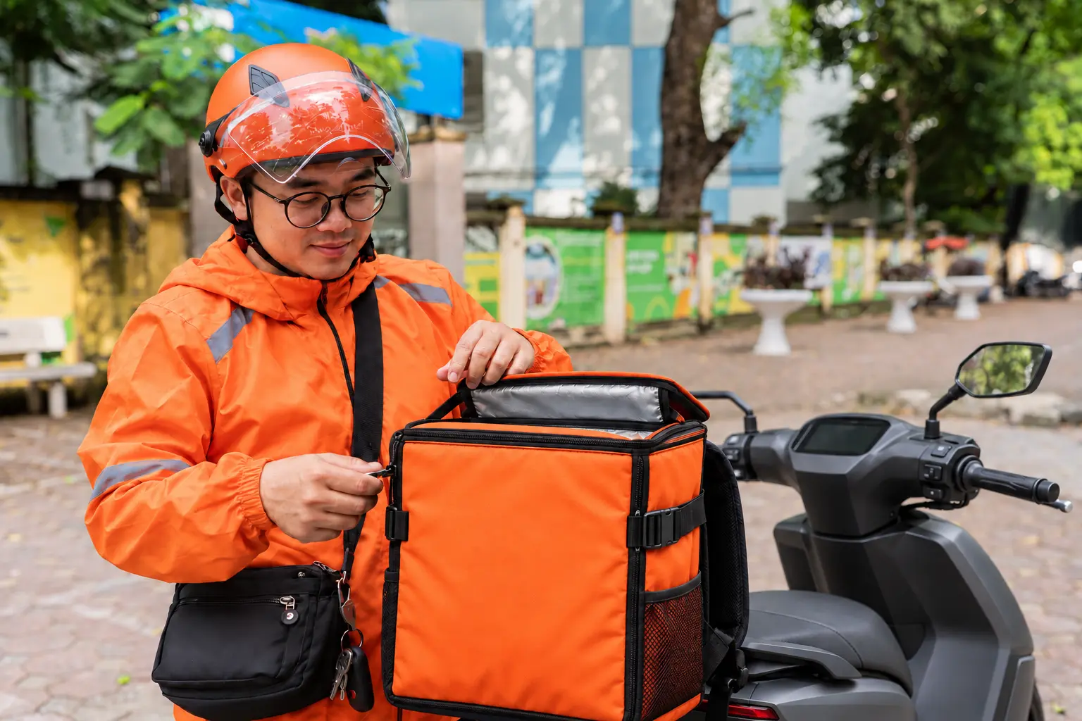 Driver preparing a delivery bag beside a motorbike